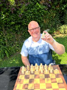 Gregory Hunt holding a carved Lewis-style chess rook, representing the role of the arbitrator in ADR — structured, authoritative, and final.